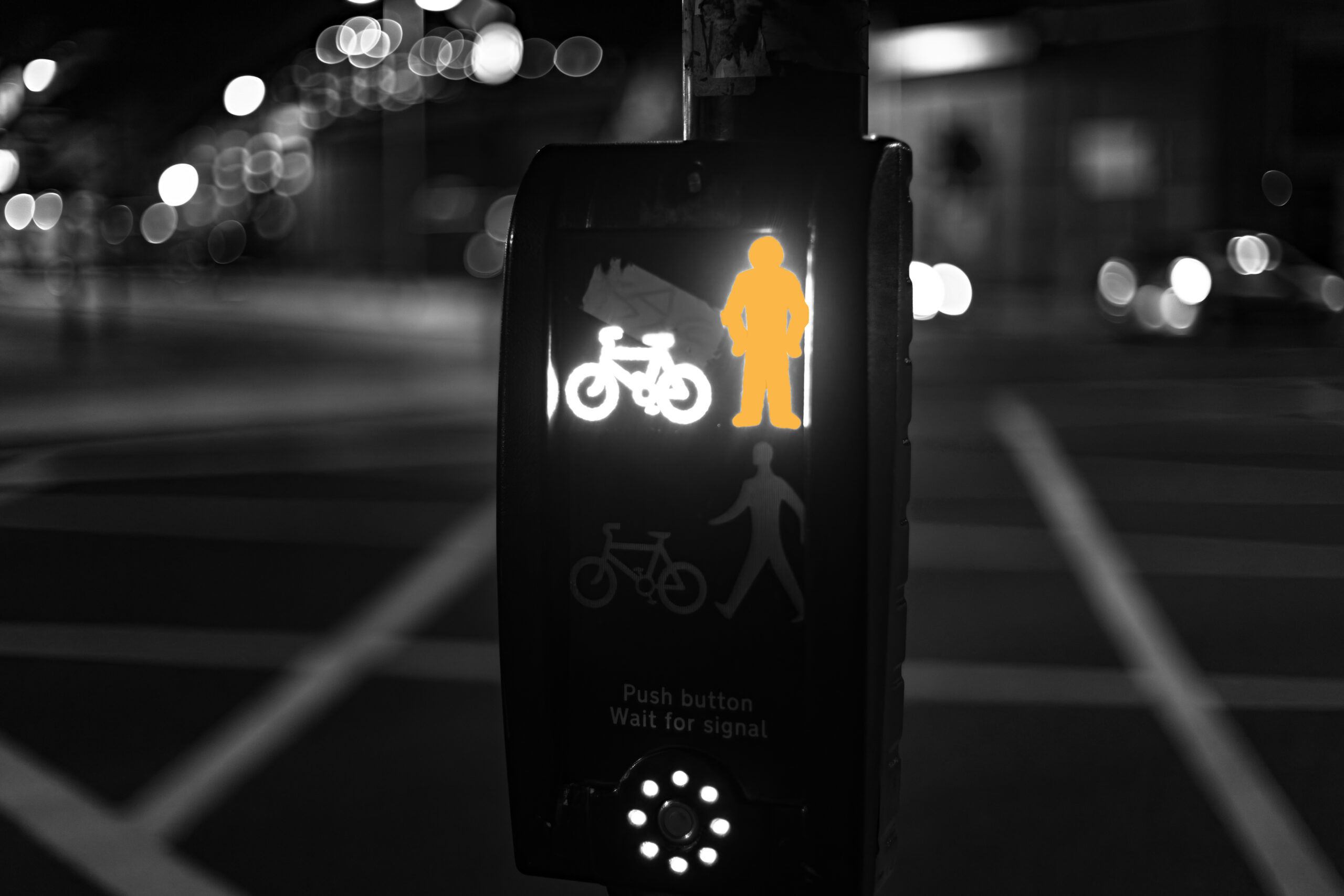 Black and white photo of a pedestrian crossing signal at night, amber standing figure illuminated, with the words ‘Push button. Wait for signal.’ representing the habit of waiting to feel ready.