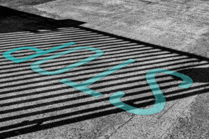 the stop-start cycle of habits. Teal painted STOP sign on a striped black and white surface. Abstract street photography representing the stop-start cycle of habit formation.