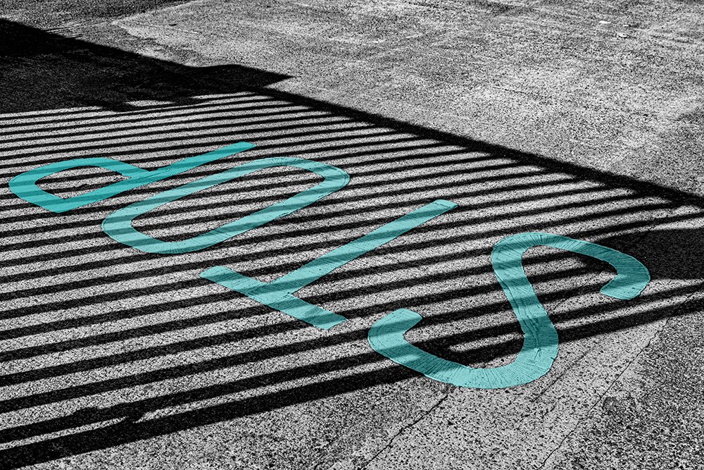Teal painted STOP sign on a striped black and white surface. Abstract street photography representing the stop-start cycle of habit formation. 