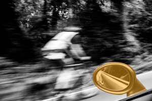 Black and white photo of a cyclist speeding past, shot from a moving car with a gold wing mirror in the foreground, representing forward momentum and questioning the road behind you.
