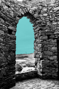Black and white stone archway with teal sky and coastline visible through the opening, representing the gap between where you are and where you want to be.
