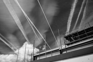 Aircraft contrails crossing the sky above a rooftop with scaffolding under construction to represent how to build a habit stack.