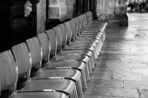 A row of stacked metal chairs lined up along a stone corridor, representing the habit stacking.