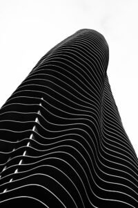 A building facade curving upward in repeating horizontal layers, photographed from below representing habit stacking ideas for everyday life.