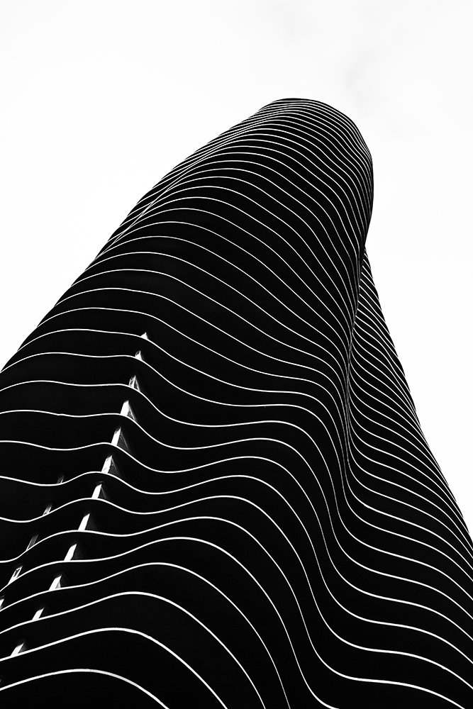 A building facade curving upward in repeating horizontal layers, photographed from below representing habit stacking ideas for everyday life. 